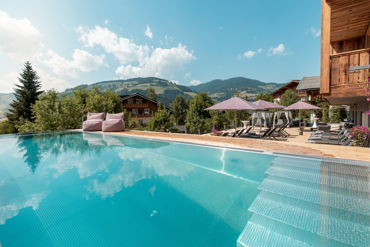 Infinity Pool mit Sonnenterrasse mit Blick auf den Bergen